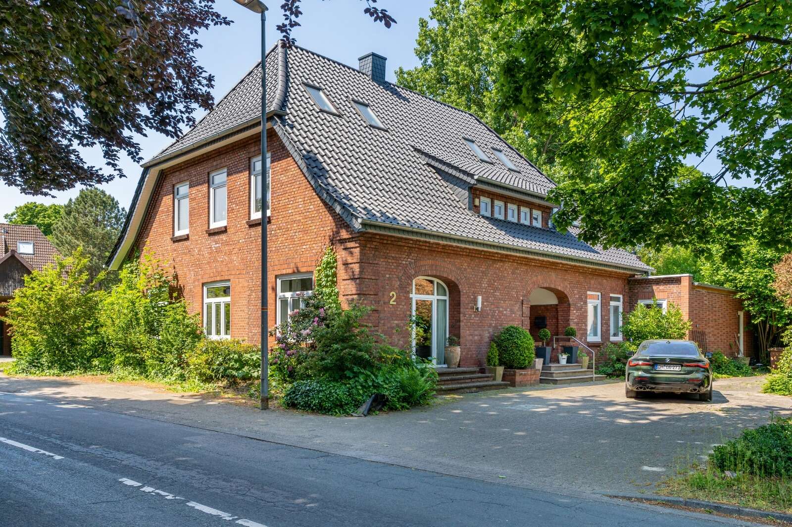 Backsteinhaus nach energetischer Sanierung mit modernem dunkelgrauen Dach und frischer Fassadengestaltung.