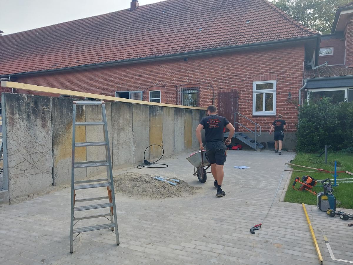 Backsteinhaus mit altem roten Ziegeldach und außenliegender Metalltreppe vor der energetischen Sanierung.