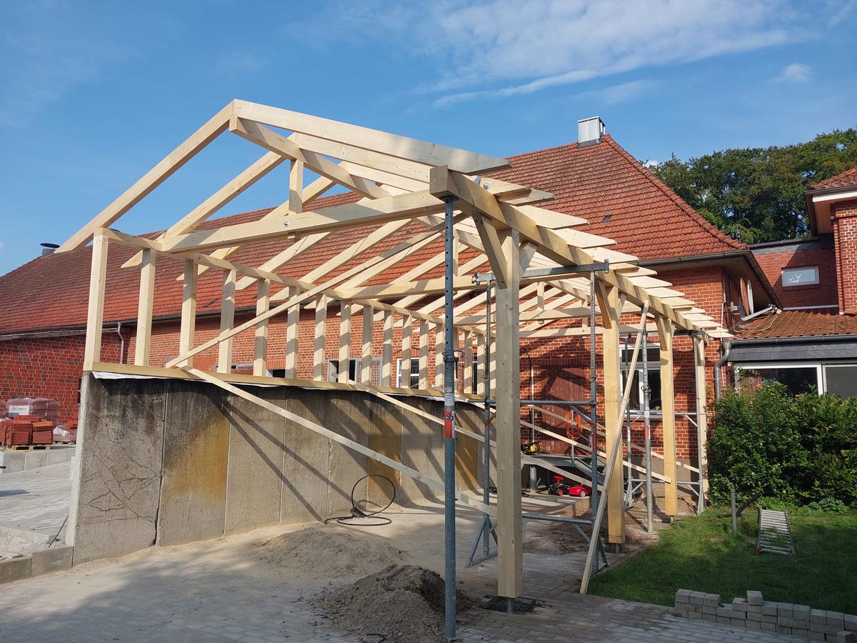 Backsteinhaus nach energetischer Dachsanierung mit neuem dunkelgrauen Ziegeldach und gepflegter Außenanlage.