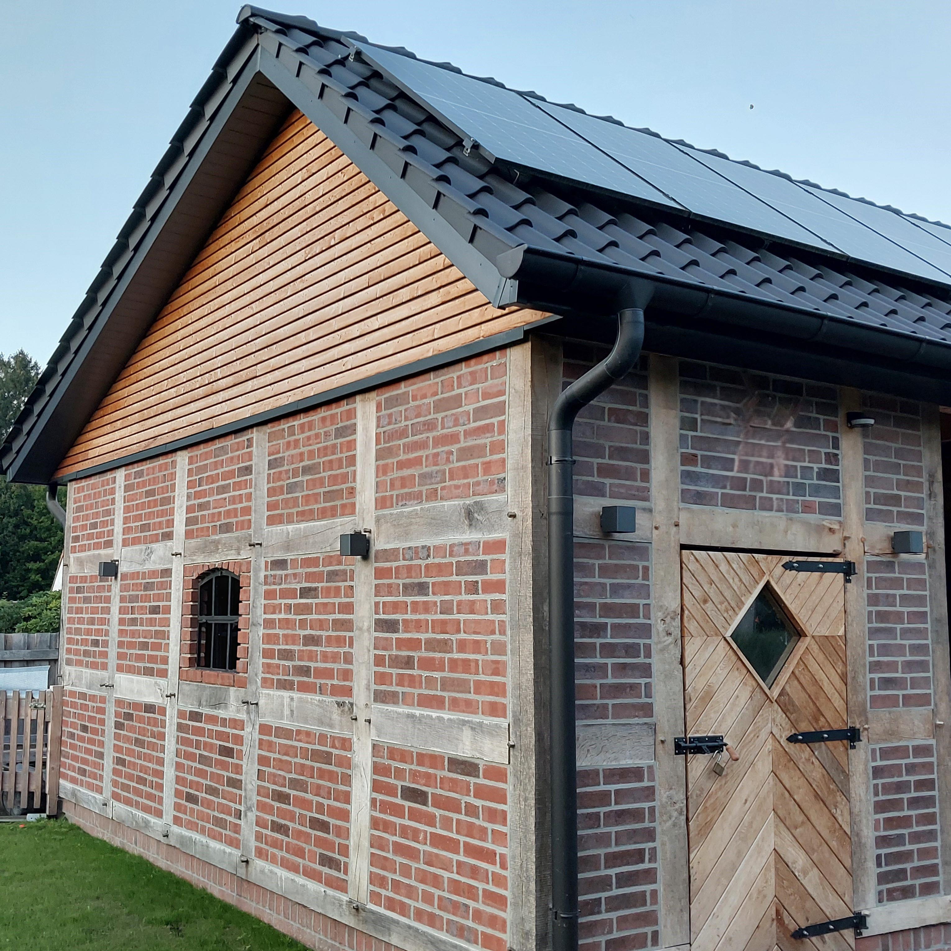 Carport im traditionellen Fachwerkstil mit Holztür aus Eichenbrettern, Kohlebrand-Klinker und Ziegeldach