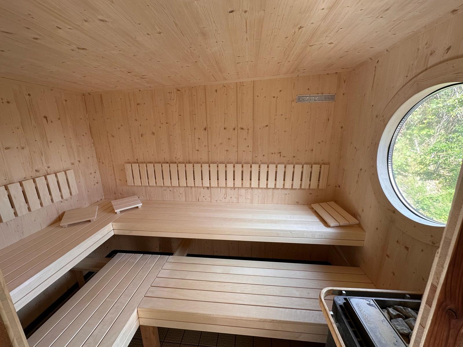Sauna nachher: L‑förmige Sitzbänke in hellem Holz, saubere Kanten und Lüftungsgitter